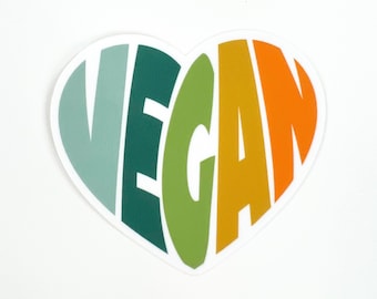 May include: A heart-shaped sticker with the word "VEGAN" spelled out in rainbow colours. The colours are teal, green, yellow, orange, and red.