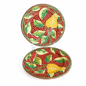 Könnte beinhalten: Zwei dekorative Teller mit Mosaikdesign. Die Teller haben einen roten Hintergrund mit grünen Blättern und gelben Birnen. Die Teller sind rund und oval, mit einem weißen Rand.