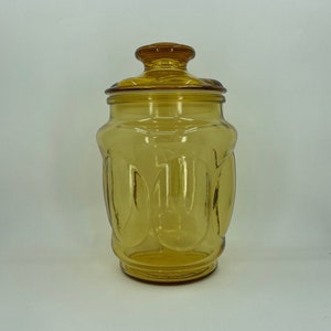 May include: Amber glass jar with a lid. The jar has a textured, rounded design.