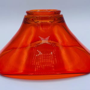 Pu&ograve; includere: Un vaso di vetro arancione brillante con una base larga e svasata e un'apertura stretta. Il vaso &egrave; in vetro trasparente con una leggera sfumatura arancione.