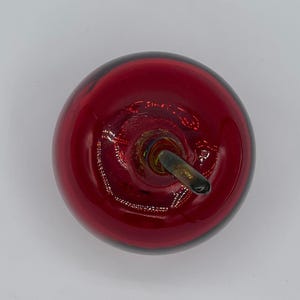 May include: A red glass apple with a black stem. The apple is a decorative object.