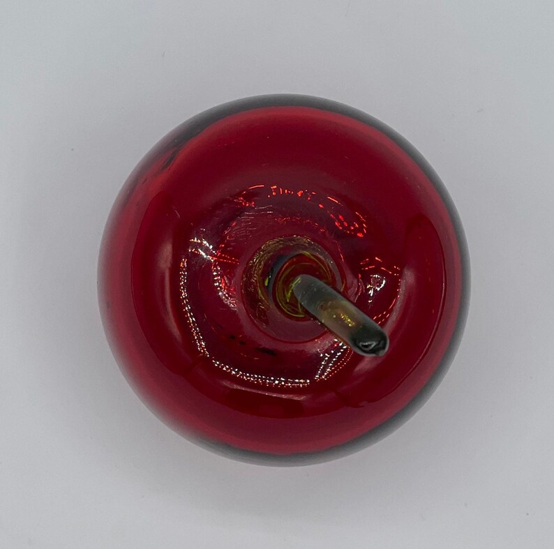 May include: A red glass apple with a black stem. The apple is a decorative object.