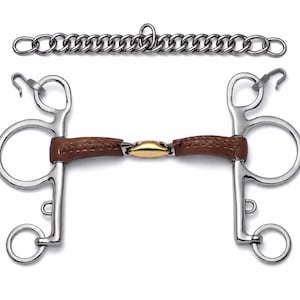 Pode incluir: Um freio para cavalo em aço inoxidável com bocal revestido em couro castanho e um elo central em metal dourado. O freio inclui duas hastes laterais com argolas e ganchos, acompanhado por uma barbela de aço inoxidável a condizer.
