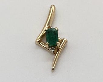 Könnte beinhalten: Ein goldener Anhänger mit einem grünen Smaragd-Edelstein und einem kleinen Diamanten-Akzent. Der Anhänger ist in Form eines Blitzes geformt.
