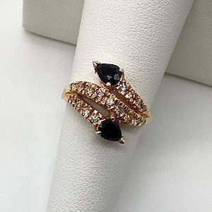 May include: A gold ring with two black gemstones and a band of small diamonds.