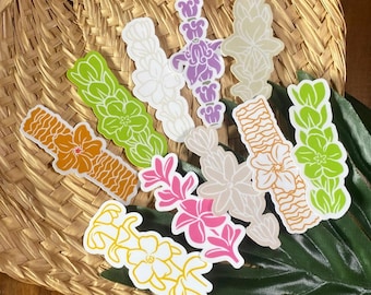 Könnte beinhalten: Eine Sammlung von zehn gestanzten Aufklebern mit Blumen- und Pflanzenmotiven in verschiedenen Farben wie Orange, Limettengrün, Weiß, Lila, Pink und Gelb, die in einem verstreuten Muster auf einer geflochtenen Oberfläche angeordnet sind.