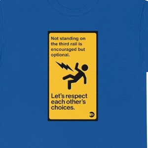 Puede incluir: Camiseta azul real con un gráfico rectangular amarillo. El gráfico presenta una figura de palo cayendo con un rayo y el texto "No pararse en el tercer carril es recomendable pero opcional. Respetemos las elecciones de los demás."