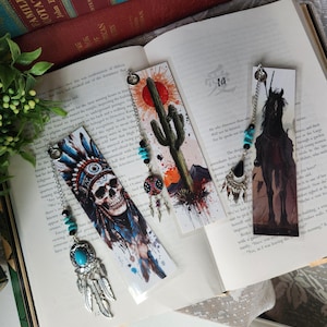 May include: Bookmarks with Native American and Southwestern themes. One features a skull in a headdress, another a cactus and sun, and a third a black horse. Each has a decorative chain with beads and charms.