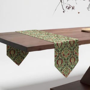 May include: A wooden dining table with a decorative green and red patterned table runner. A vase with branches and a white sphere sit on the table. The table has a dark brown finish and a unique geometric base.