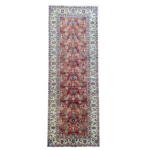 May include: A long, narrow rug with a floral pattern in shades of red, blue, and white. The rug has a cream-colored border with a repeating floral design.