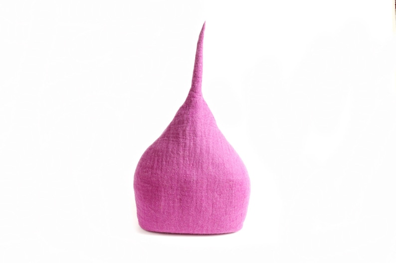 May include: A magenta hat with a conical shape and a long, pointed tip. The hat has a textured surface and is set against a white background. The hat appears to be made of felt.
