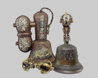May include: A set of two ornate Tibetan prayer bells, one with a handle and the other with a bell clapper. The bells are made of brass and have intricate designs.