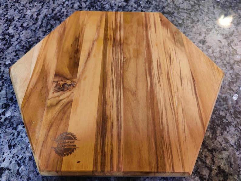 A back view of a hexagon shaped cutting board, with our logo laser engraved.