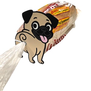 May include: A tan pug dog-shaped plastic bag dispenser with a black nose, ears, and eyes, and a pink tongue. The dispenser is attached to a clear plastic bag, and a loaf of bread is in the background.