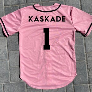 May include: Pink baseball jersey with black trim and the word "KASKADE" and the number "1" printed on the back.