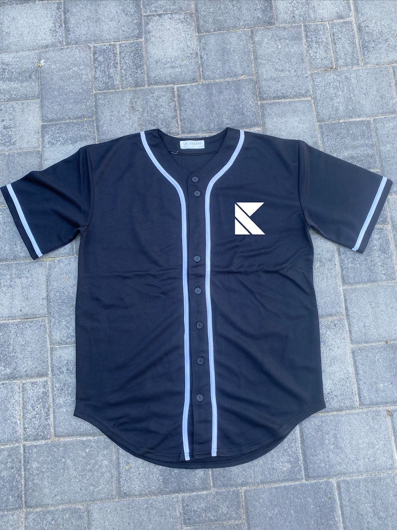 May include: Black baseball jersey with white trim and a white letter K logo on the front.