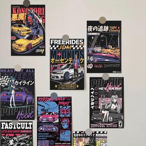 May include: A collection of colorful JDM (Japanese Domestic Market) car art prints. Each print features stylized illustrations of cars, anime-style characters, and Japanese text. The prints are in various sizes and designs, with a black background.