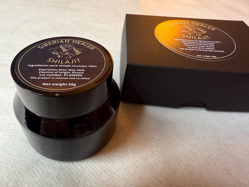 May include: A black jar with a label that reads "Siberian Healer Shilajit" with the ingredients, expiration date, country of origin, lot number, and net weight of 50g. The jar is sitting on a white surface.