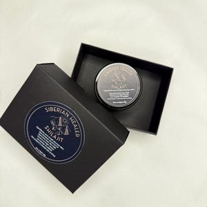 May include: A black box with a gold logo that says "Siberian Healer Shilajit" with a mountain and tent design. The box is open and a small black jar with a gold lid is inside. The jar has a gold label that says "Siberian Healer Shilajit" with a mountain and tent design. The jar is 30g.