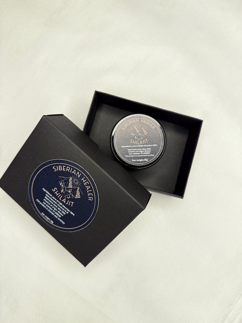 May include: A black box with a gold logo that says "Siberian Healer Shilajit" with a mountain and tent design. The box is open and a small black jar with a gold lid is inside. The jar has a gold label that says "Siberian Healer Shilajit" with a mountain and tent design. The jar is 30g.