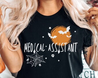May include: Black t-shirt with a white graphic of a spider web, bats, and a moon with the text "Medical Assistant".