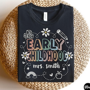 May include: Black t-shirt with the words "EARLY CHILDHOOD" in colorful letters, surrounded by white illustrations of flowers, a pencil, ABC blocks, a rainbow, and an apple. The text "mrs. smith" is below the main text.
