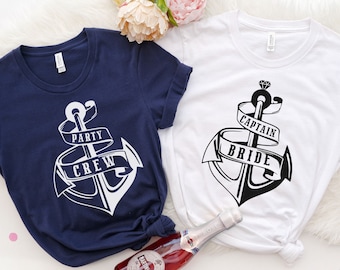 May include: Two t-shirts with an anchor graphic. One shirt is navy blue with white text that says "Party Crew". The other shirt is white with black text that says "Captain Bride".