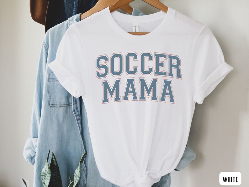 May include: White t-shirt with blue and red text that says "Soccer Mama".