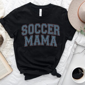 May include: Black t-shirt with the text "SOCCER MAMA" in blue and pink lettering.