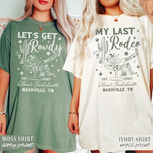 May include: Two t-shirts with a bachelorette party theme. The green shirt says "Let's Get Rowdy" with a cowgirl riding a glass of champagne. The ivory shirt says "My Last Rodeo" with a cowgirl riding a glass of champagne. Both shirts have the text "Olivia's Bachelorette 2025 Nashville, TN".