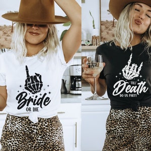 Puede incluir: Dos mujeres con camisas a juego con un gr&aacute;fico de mano de esqueleto. La camisa blanca dice "Bride or Die" y la camisa negra dice "Till Death Do Us Party". Ambas mujeres llevan faldas de estampado de leopardo y sombreros marrones.