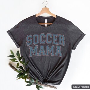 May include: Dark grey heather t-shirt with the text "SOCCER MAMA" in blue and pink lettering.