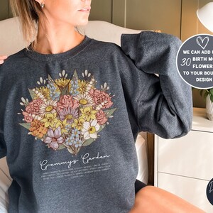 May include: Dark grey heather sweatshirt with a floral bouquet design and the text "Grammy's Garden" printed on the front. The text below the bouquet lists the names of different flowers.