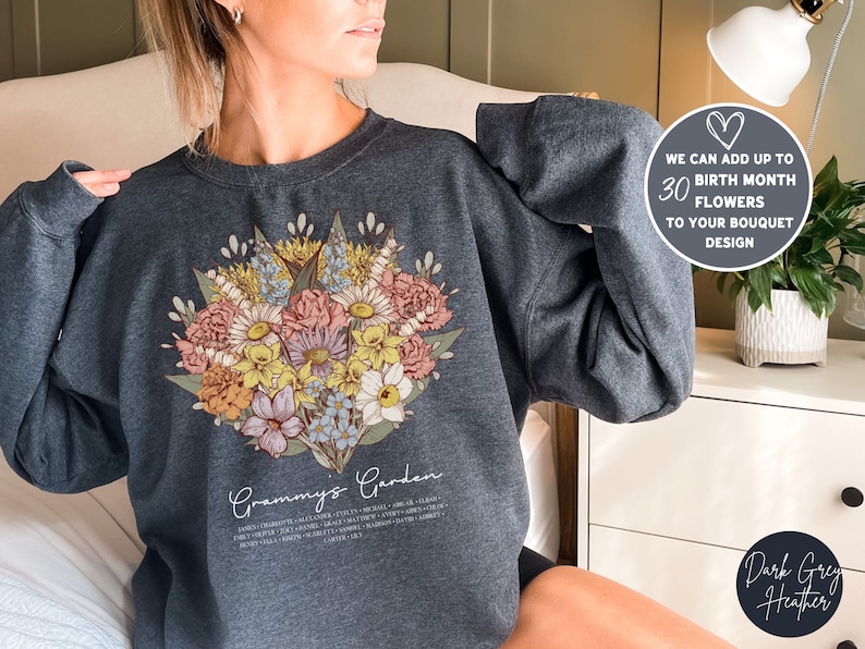 May include: Dark grey heather sweatshirt with a floral bouquet design and the text "Grammy's Garden" printed on the front. The text below the bouquet lists the names of different flowers.