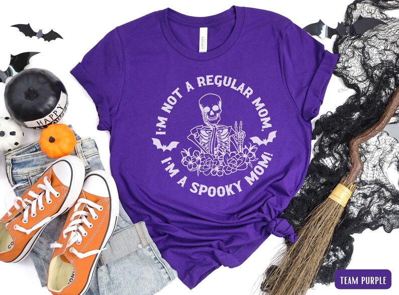 May include: Purple t-shirt with a white skeleton graphic and the text "I'm not a regular mom, I'm a spooky mom!"