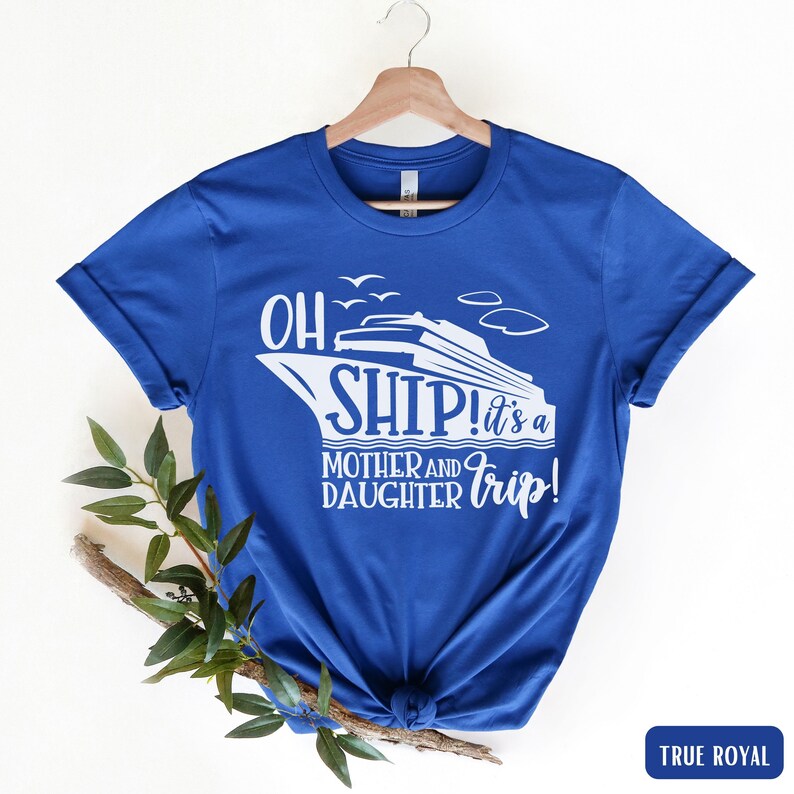 May include: A royal blue t-shirt with a white graphic of a cruise ship and the text "Oh Ship! It's a Mother and Daughter Trip!"