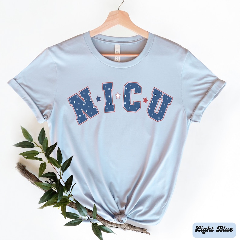May include: Light blue t-shirt with the text "N.I.C.U." in blue and red letters with white stars.