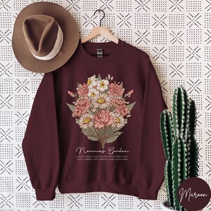May include: Maroon sweatshirt with a floral bouquet design and the text "Nonnie's Garden" with a list of names below.