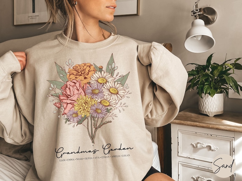May include: A beige sweatshirt with a floral design and the text "Grandma's Garden" with a list of names below.