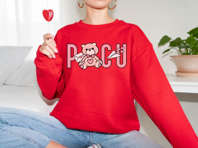 Peut inclure: Sweat-shirt rouge avec un ourson rose tenant une lettre et le mot "POCU" imprim&eacute; sur le devant.