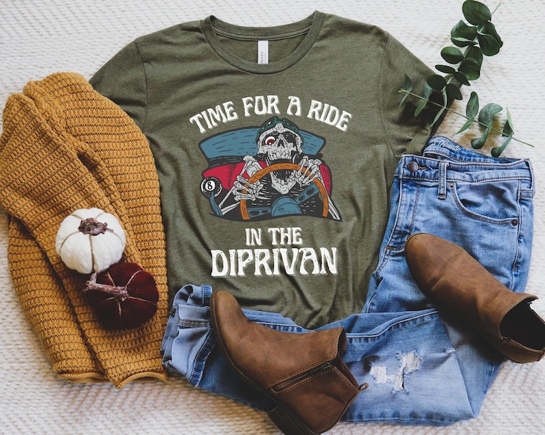 May include: A green t-shirt with the text "Time for a ride in the dip-rivan" and a cartoon skeleton driving a car. The skeleton is wearing a pirate hat and holding a steering wheel. The car has a skull and crossbones on the side.