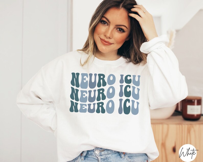 Pode incluir: Camisola branca com o texto "NEURO ICU" repetido tr&ecirc;s vezes em uma fonte retr&ocirc; azul e verde.