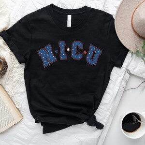 May include: Black t-shirt with a blue and red "NICU" graphic with white stars. The shirt is made of a soft, comfortable material.