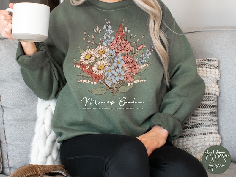 May include: A green sweatshirt with a floral design and the text "Mimi's Garden" printed on the front. The flowers are in shades of pink, white, and blue.