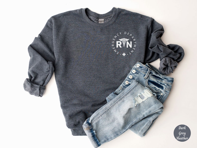 Peut inclure: Sweat-shirt gris fonc&eacute; chin&eacute; avec un graphique circulaire blanc qui dit "Emergency Department RN" avec un symbole de caduc&eacute;e.