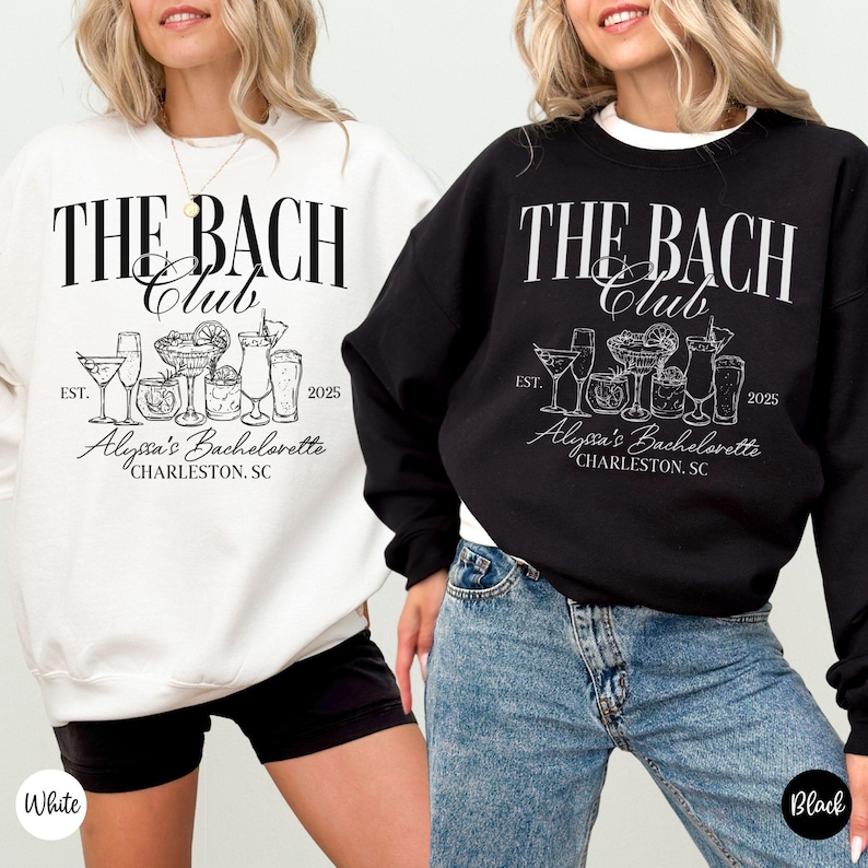 K&ouml;nnte beinhalten: Zwei wei&szlig;e und schwarze Sweatshirts mit dem Text "The Bach Club" und einer Grafik von Cocktailgl&auml;sern. Der Text "EST. 2025" und "Alyssa's Bachelorette" sind ebenfalls auf den Sweatshirts enthalten. Das wei&szlig;e Sweatshirt wird von einer Person mit schwarzen Shorts getragen und das schwarze Sweatshirt von einer Person mit blauen Jeans.