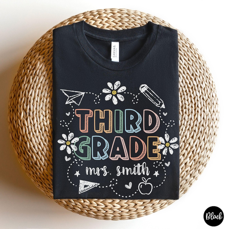 May include: Black t-shirt with a white design that says "Third Grade Mrs. Smith" with colorful rainbow letters and a drawing of a pencil, ruler, and flowers.