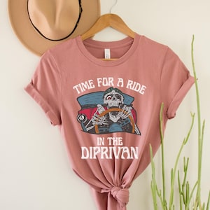 May include: A pink t-shirt with a skeleton driving a car and the text "Time for a ride in the Diprivan".