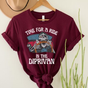 May include: A maroon t-shirt with a graphic of a skeleton driving a car with the text "Time for a ride in the Diprivan".