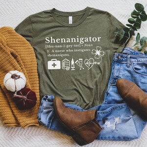 May include: A green t-shirt with the text "Shenanigator [Shu-nan-i-gey-ter]. Noun 1. A nurse who instigates shenanigans." and a variety of medical symbols.